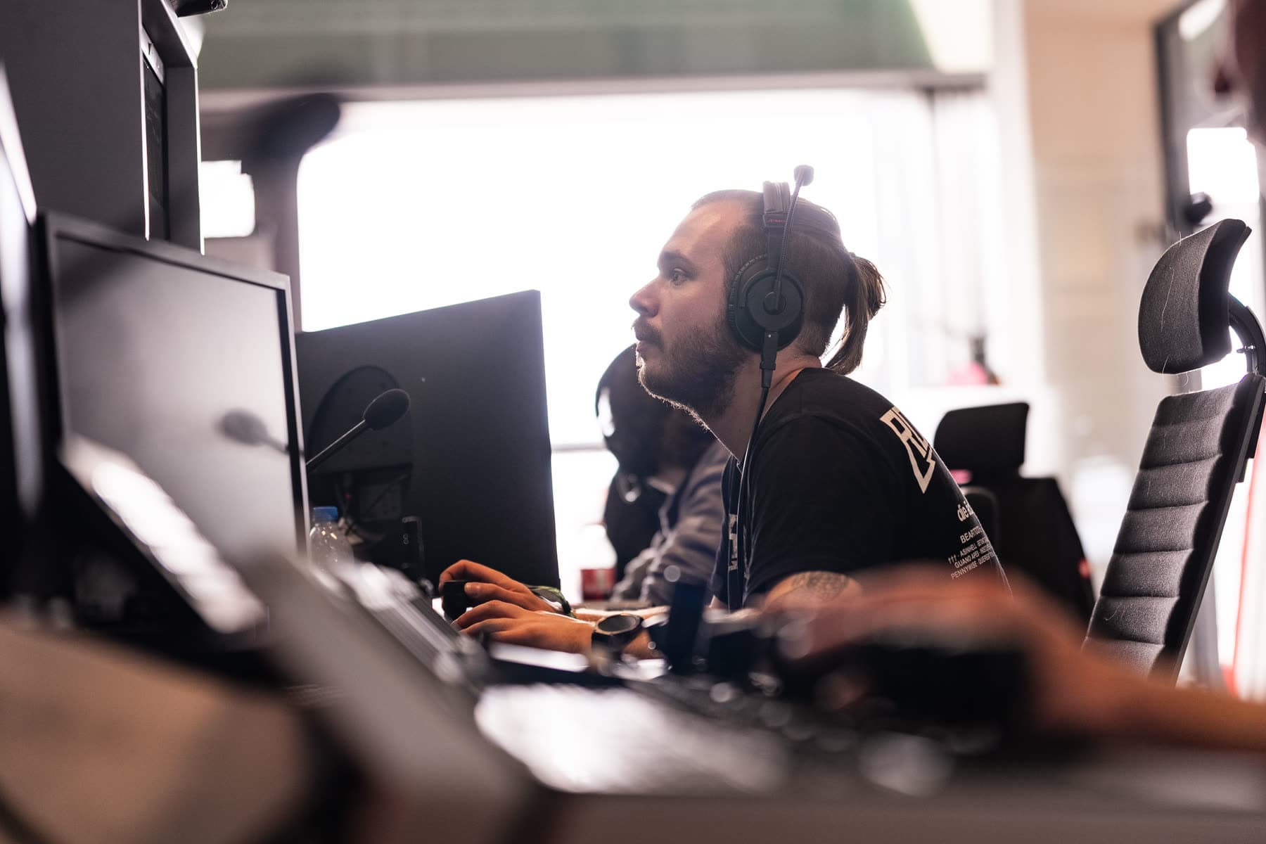 Regisseur mit Headset vor der Monitorwand