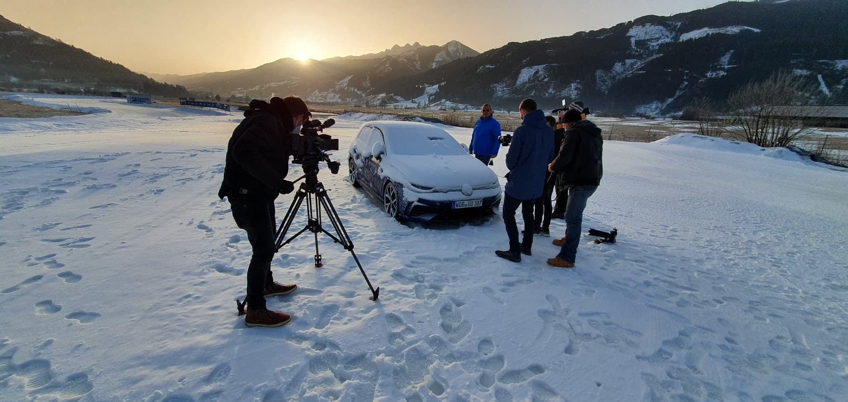 Shooting in snow: camera on a tripod in front of a snow-covered car