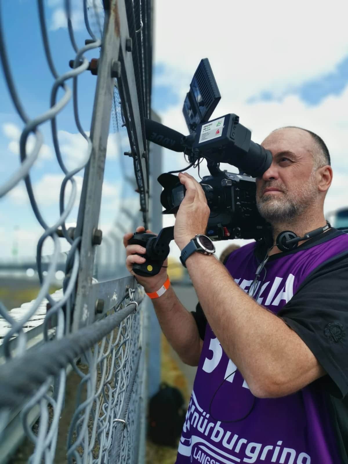 Camera operator shooting through the track fence